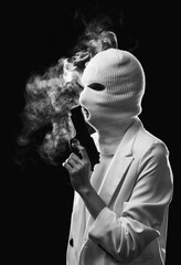 A woman in a white balaclava mask with a gun near his face on a dark background with smoke.
