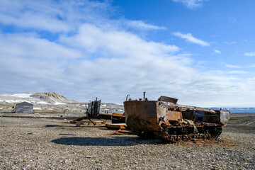 Fototapeta na wymiar Rusted old snow machine and other equipment at research station at Kinnvika, historic artifacts, Murchison Fjord, Hinlopen Straight, arctic expedition tourism around Svalbard 