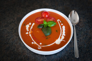 ready to eat - homade hot tomato soup in a white bowl with basil, cherry tomatoes, creamy and croutons