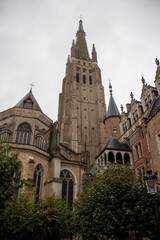 Fototapeta na wymiar The Towering Spire of the Church of Our Lady in Bruges Against a Cloudy Sky - Medieval Brickwork Marvel