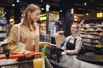 Young customer woman in casual clothes give seller cashier credit bank card at checkout shopping at...