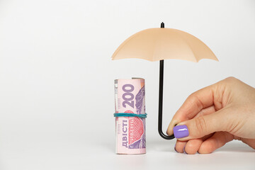 200 hryvnia under a small umbrella in a girl s hand on a white background, business and finance in Ukraine