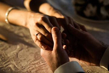 Intimate Moment of Couple Holding Hands with Engagement Ring in Warm Light