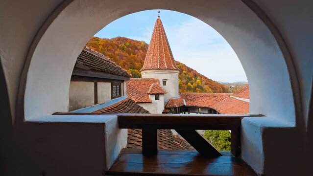 Old-fashioned tiled rooftops of the Bran castle, Brasov, Romania. Amazing colorful mountain covered with bright forest at backdrop.