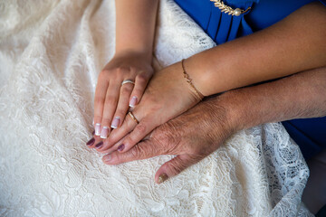 Bride's, mother's, and grandmother's hands on lace wedding dress