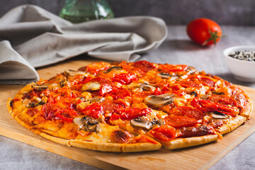 St. Louis Style pizza with bacon, mushrooms, tomatoes and peppers on a board on the table
