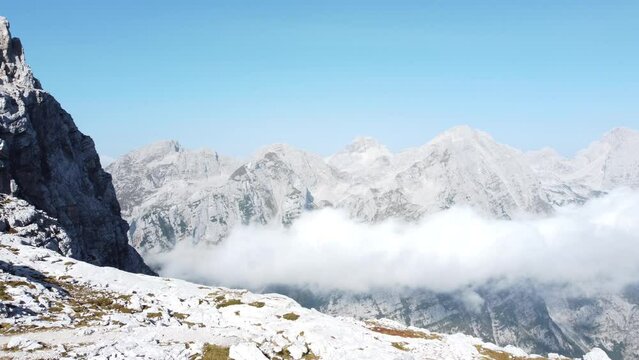 Majestic high mountain peaks in Alpes with misty clouds beneath in a valley and light blue clear sky above. Triglav mountain, Slovenia.