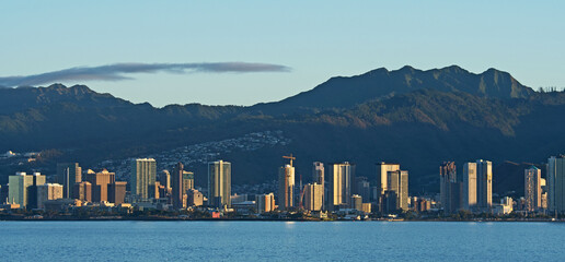 Seen from the Pacific Ocean, the morning sun shines of the tall buildings of the Honolulu skyline.