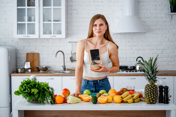 Woman in Kitchen Engaged in Culinary Reading. A woman standing in a kitchen holding a book