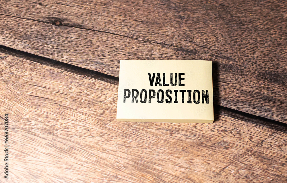 Poster value proposition text on notebook with pen and pencil on a grey background.