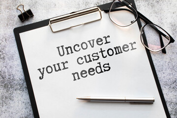 Uncover Your Customer Needs . gray and yellow background. text on white notepad paper.
