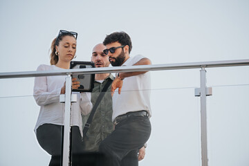 Confident business partners discuss project details outdoors, analyzing statistics and profitability. Successful teamwork and communication for remote work in the urban city.