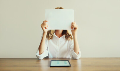 Woman showing and holding white blank sheet of paper document for text copy space while working...