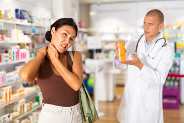 Woman complains to a pharmacist about a sore throat. Help in choosing a medicine in a pharmacy