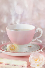 Pink mug book and flowers on a blurred background with spots of light and rays. Soft focus. Vertical image. greeting card