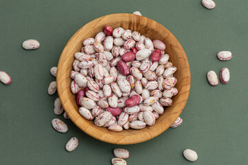 Top view full frame background of healthy dried uncooked white bean seeds on the wooden bowl.