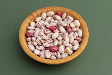 Top view full frame background of healthy dried uncooked white bean seeds on the wooden bowl.