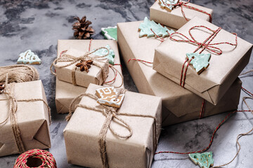 Wrapping rustic eco Christmas packages with brown paper and string on dark background