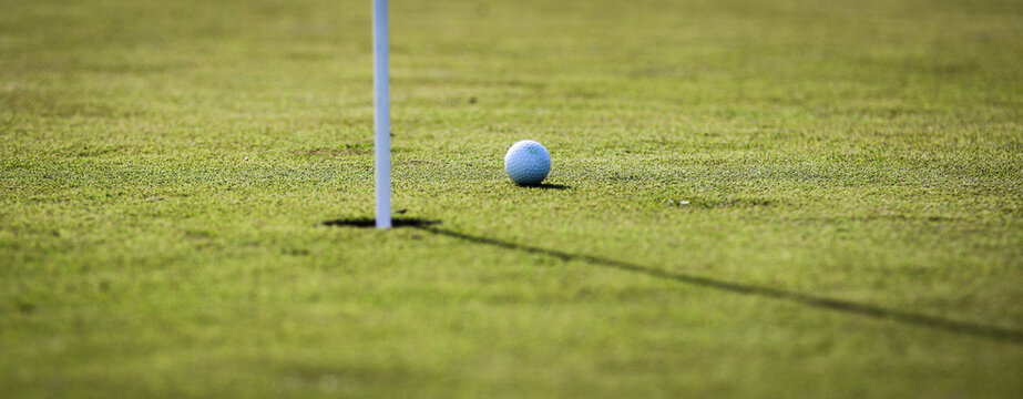 White golf ball next to putting green hole waiting to be tapped in at a golf course in Central Florida - Powered by Adobe