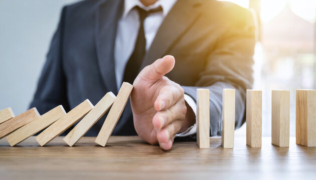 hand ob a businessman hand stop falling wooden bar from domino as symbol for intervention in crisis, risk management and analy