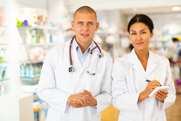 Portrait of two pharmacists - men and women in white coats in a pharmacy