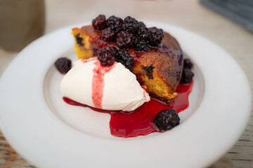 baked blackberries on top of almond and olive cake with cream fresh.