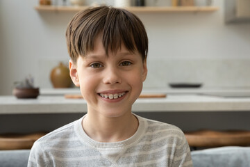 Happy early teenage boy with dental metal braces on teeth looking at camera, smiling during online conference chat, video call. Pre teen pupil kid, school student home head shot portrait
