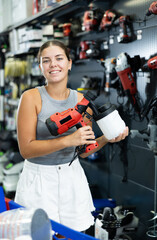 Fototapeta na wymiar Woman chooses and buys paint spray gun in a hardware store