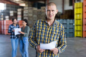Man standing and holding document in hands. His female colleagues standing behind him.