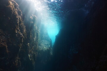 Rocky underwater landscape in the Mediterranean sea, narrow passage with sunlight through water...
