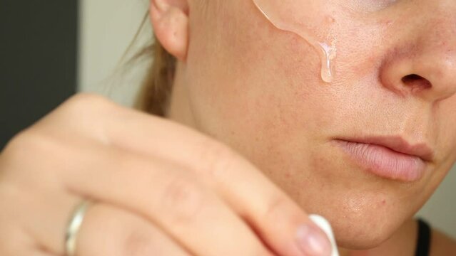 Close up portrait of caucasian woman applying face serum on skin, face and neck 