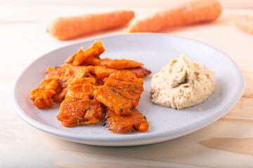 Baked carrot chips and chickpea hummus. Tasty vegan snack idea.