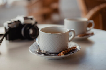 Two cups of coffee and a vintage analogue camera on a table - Powered by Adobe