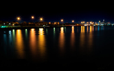Fototapeta na wymiar Streetlamps Reflecting in Lake Erie with Cleveland in the Distance
