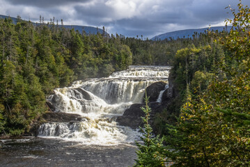 Baker's Brook Falls and coniferous forest in Gros Morne Newfoundland under dark storm clouds
