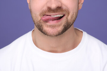 Obraz premium Man showing his tongue on purple background, closeup