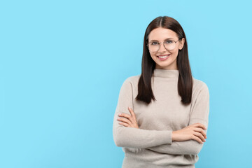Portrait of smiling woman in stylish eyeglasses on light blue background. Space for text