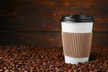 Coffee to go. Paper cup and roasted beans against wooden background, space for text