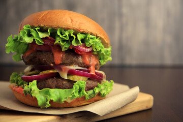 Board with tasty burger on wooden table, closeup. Space for text