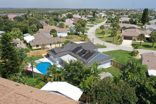 Aerial of Daytona Beach area residential neighborhood, featuring a home with an in-ground swimming pool and solar panels on the roof. 