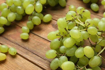 Delicious fresh green grapes on wooden table, closeup. Space for text