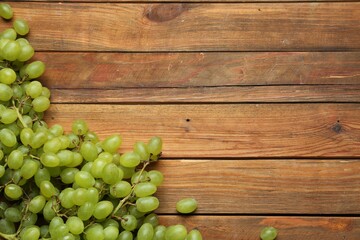 Delicious fresh green grapes on wooden table, flat lay. Space for text