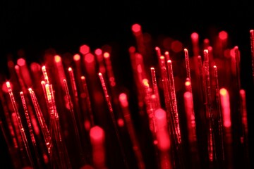 Optical fiber strands transmitting red light on black background, macro view