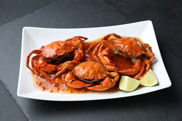 Delicious boiled crabs with sauce and lime on black textured table