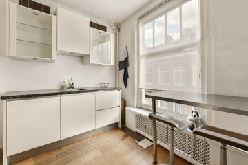 a kitchen area with white cupboards and appliances on the counter, in front of a window that is open