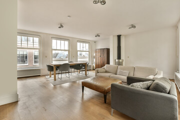 a living room with couches, chairs and a dining table in the center of the room is white walls