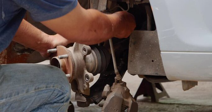 Close up Mechanic man hands repairing car auto repair shop uses jack change tyre. Man hands fixing Shock absorber machinery vehicle mechanical service. Vehicle Car overhaul maintenance engineer
