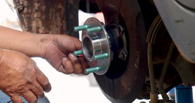 Close up Mechanic man hands repairing car auto repair shop uses jack change tyre. Man hands fixing Shock absorber machinery vehicle mechanical service. Vehicle Car overhaul maintenance engineer