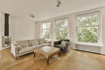 a living room with wood flooring and large windows looking out onto the trees in the photo is taken from inside