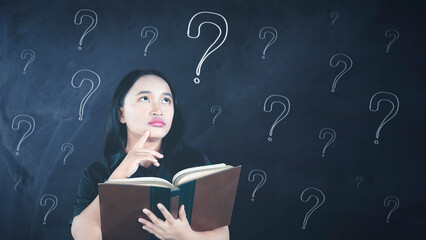 Asian woman reading a book finding answers with question marks